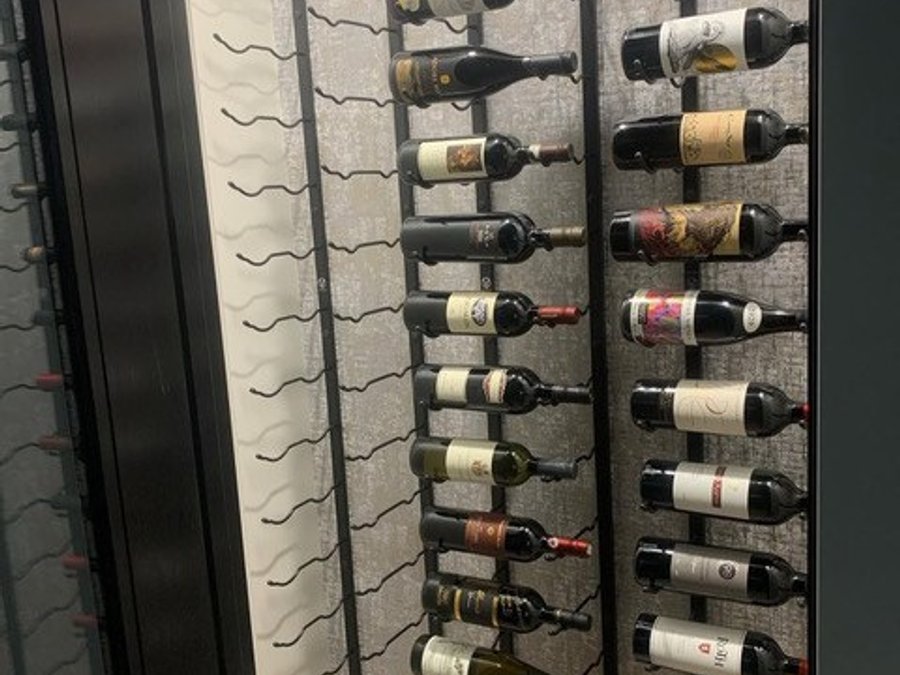 Custom wine-rack wall with metal bottle display in a finished basement bar