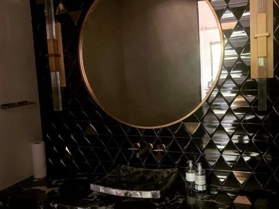 Luxury powder room with black diamond tile, a marble vessel sink, and rose-gold mirror