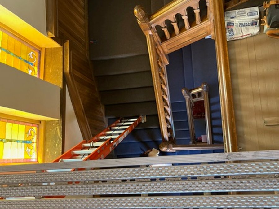 Ornate wood staircase with stained glass overhead during cathedral restoration