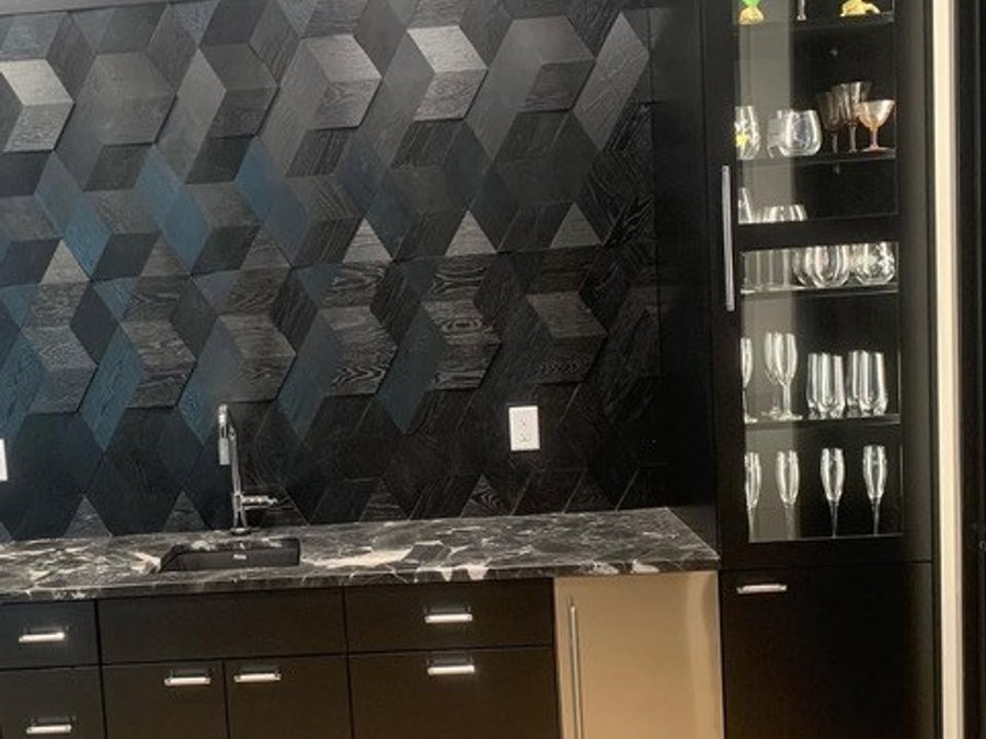Basement luxury wet bar with dark cabinetry, 3D geometric tile backsplash, marble counter, and beverage fridge
