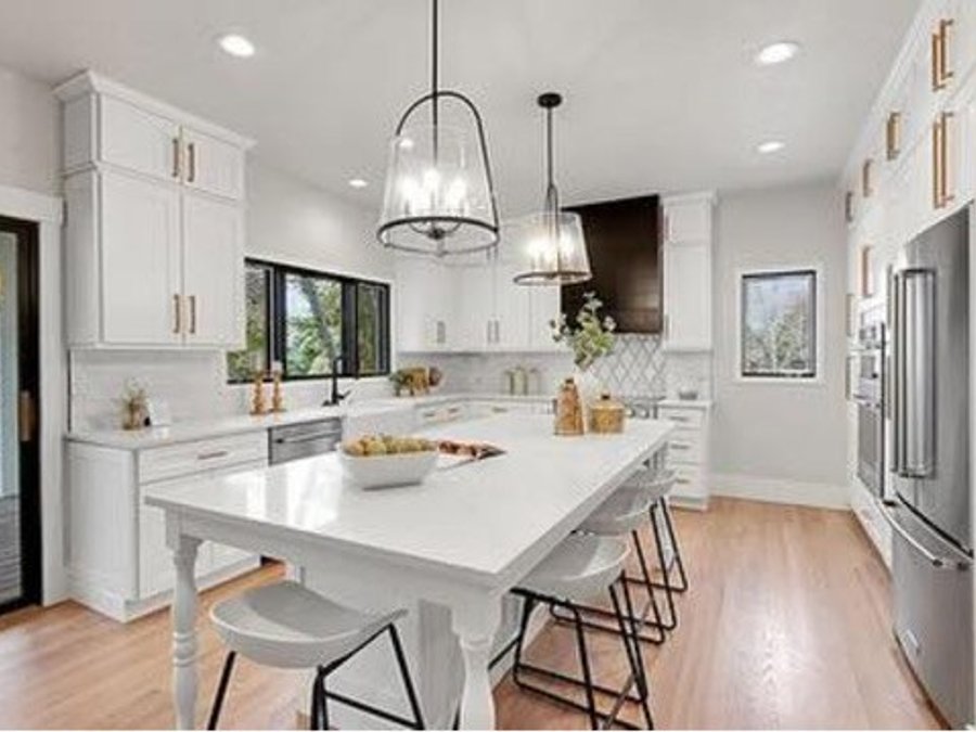 Kitchen island with pendant lights and bar stools alongside white cabinets