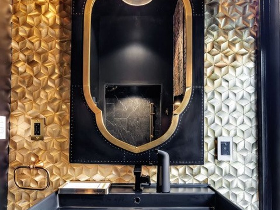 Luxury powder room with gold 3D tile, a matte-black trough sink, and an ornate mirror