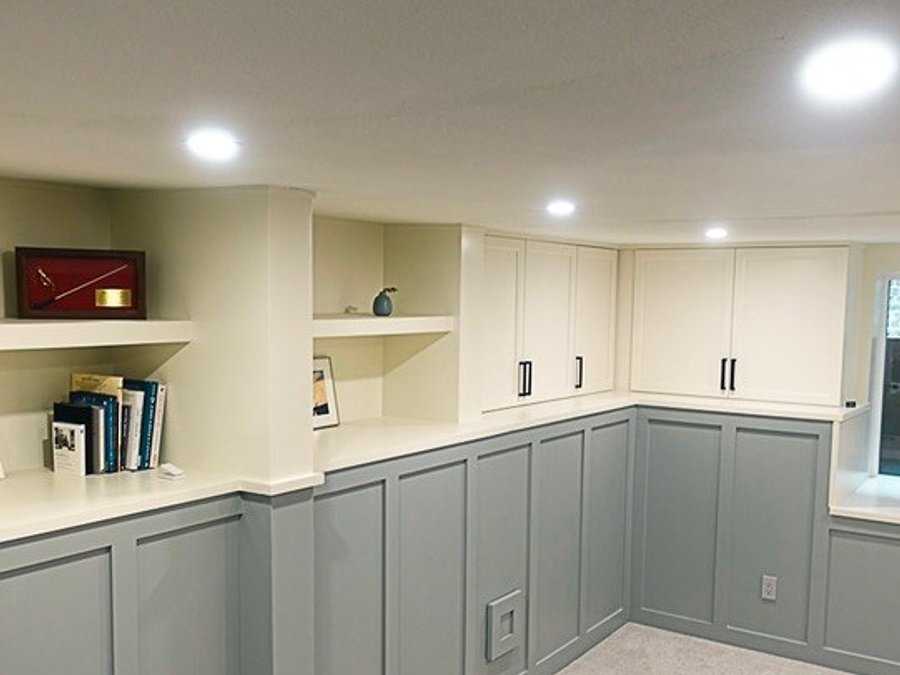 Basement corner with built-in storage, open shelving, white cabinets, and recessed lighting