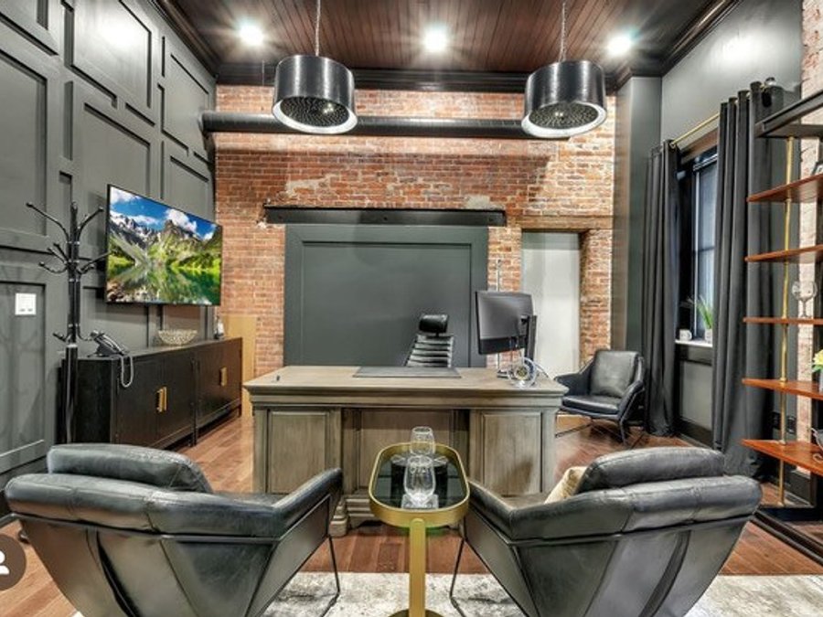 Executive office remodel with coffered paneling, exposed brick, and wall-mounted TV