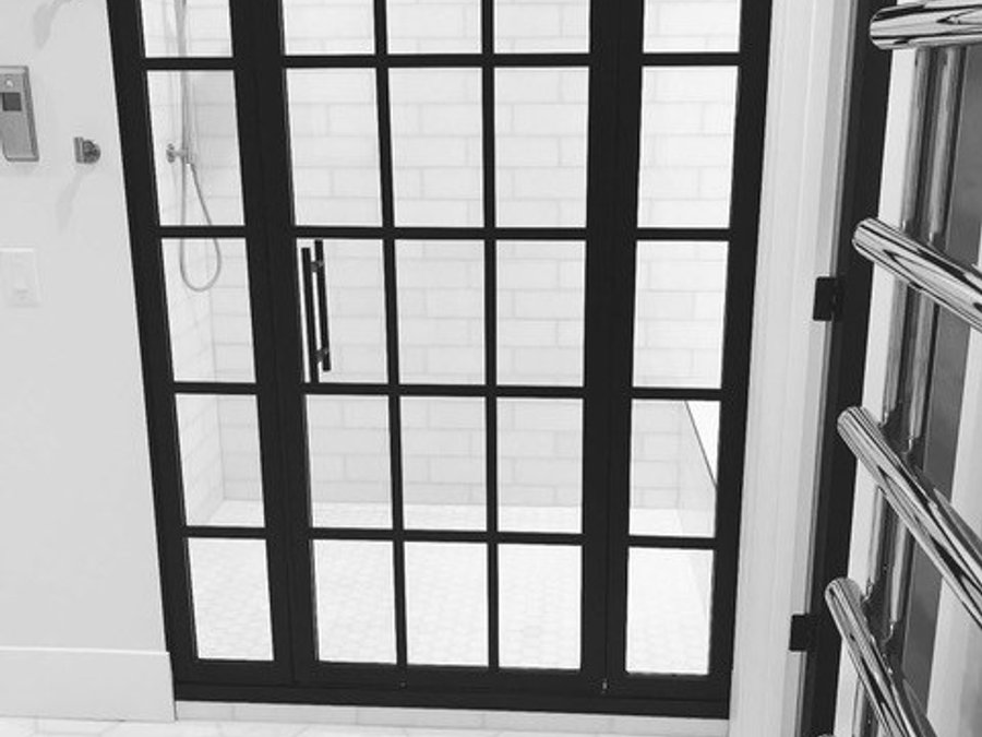 Luxury bath with black steel-frame shower door, white subway tile, and hexagon tile floor