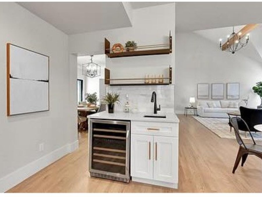 Wet bar with a wine fridge and floating walnut shelves adjoining the kitchen