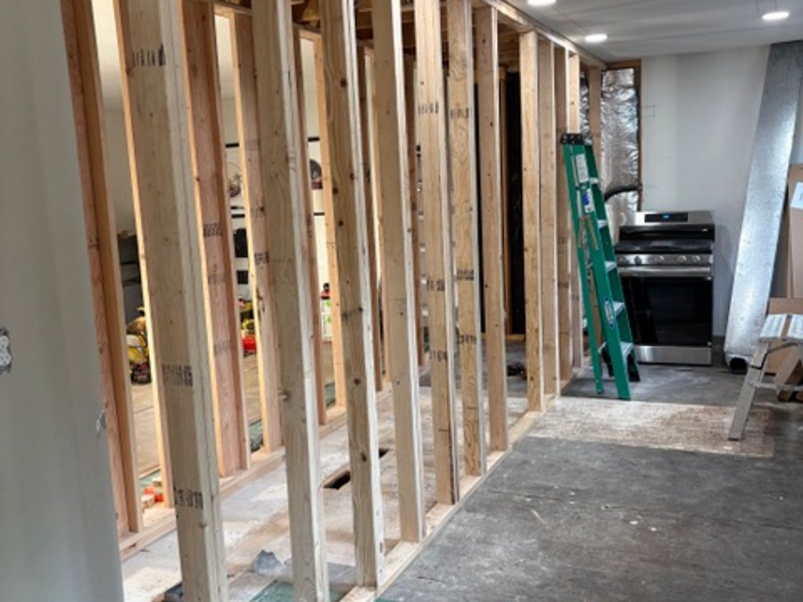 Wall framing with recessed lights and an open floor plan after beam install