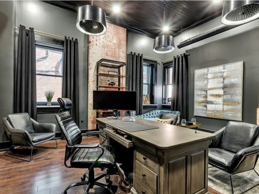 Luxury office with a teal Chesterfield sofa, industrial lighting, and hardwood floors