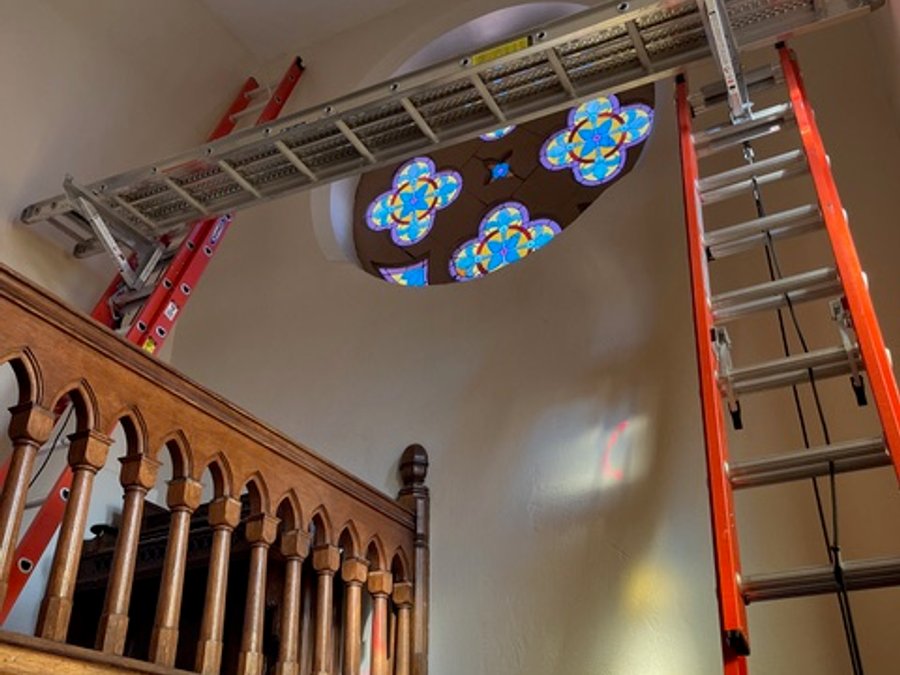 Cathedral rose window stained glass installation during ceiling repair