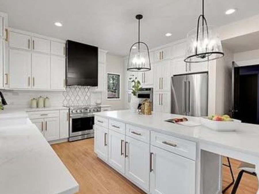 Kitchen with a black range hood, quartz island, and gold hardware
