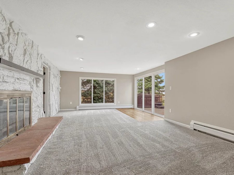 Finished: living room with stone fireplace, recessed lighting, and new carpet