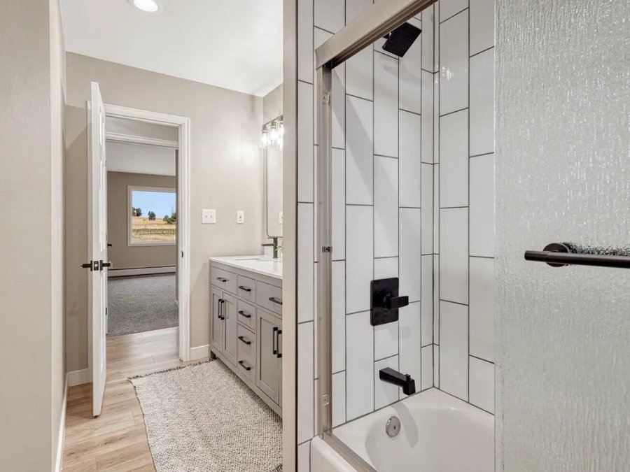 Finished: bathroom with white tile shower, gray vanity, and black fixtures