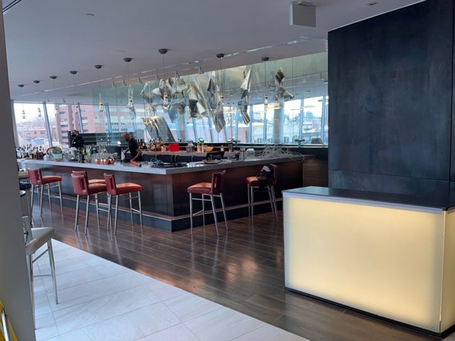 Finished hotel bar with metallic sculpture, pendant lights, and red stools